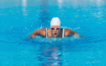 Female swimmer practices dolphin technique in outdoor pool. Swimming style, fitness, water sport, active woman, healthy lifestyle
